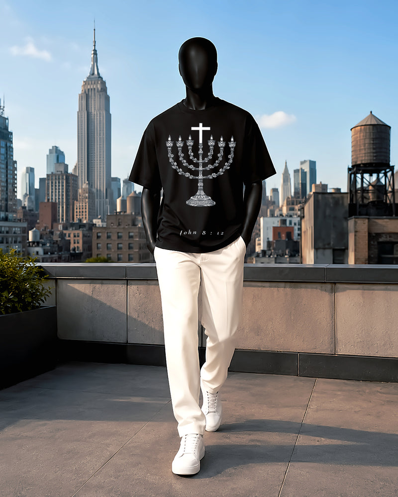 Front: Black oversized Nexus Luxora tee with white and gold menorah rising into a cross, 